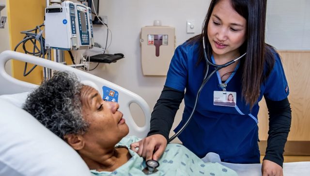 A nurse is checking a patient with a stethoscope