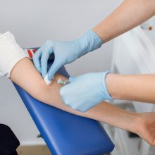 Phlebotomist inserting needle into a patient's arm to draw blood