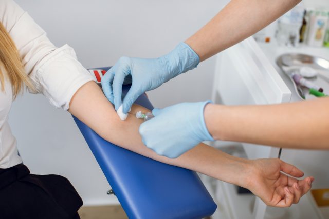 Phlebotomist inserting needle into a patient's arm to draw blood