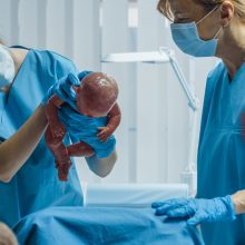 A midwife nurse holding a newborn after being born