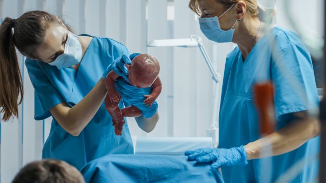 A midwife nurse holding a newborn after being born