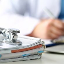 Stethoscope head lying on medical forms closeup