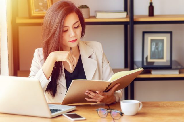 young Asian business woman working at workplace. beautiful Asian woman in casual suit working with reading book, prepare for meeting or interview in modern office. freelance and start up business in Asia