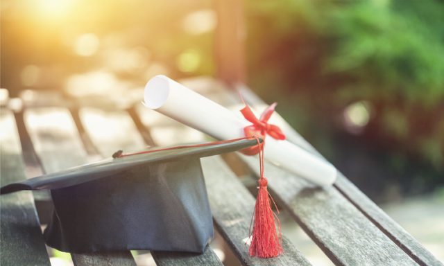 Graduation hat with tassel, diploma with red ribbon